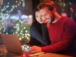 man and woman looking on silver laptop while smiling