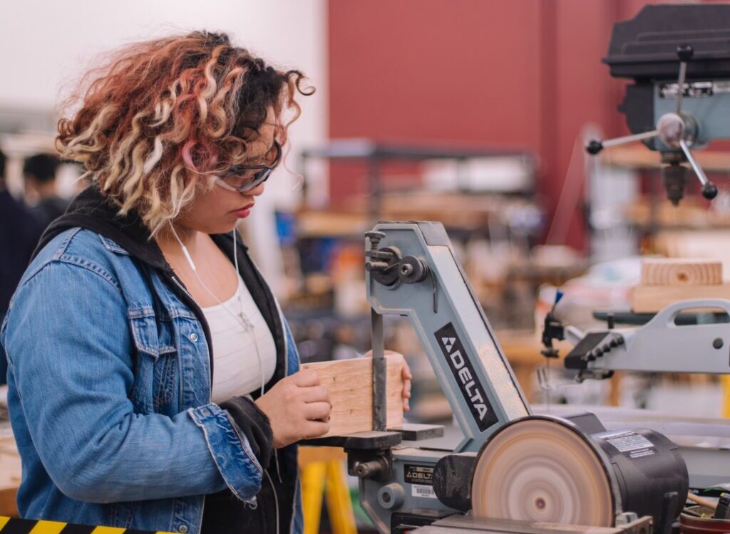 woman in blue denim jacket holding white and black power tool