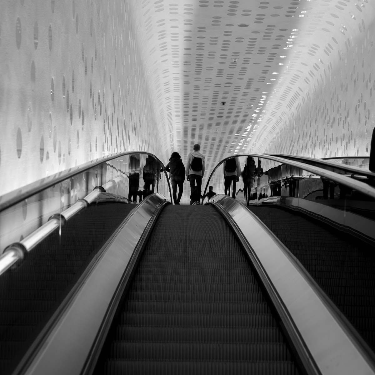 grayscale photo of people walking on tunnel