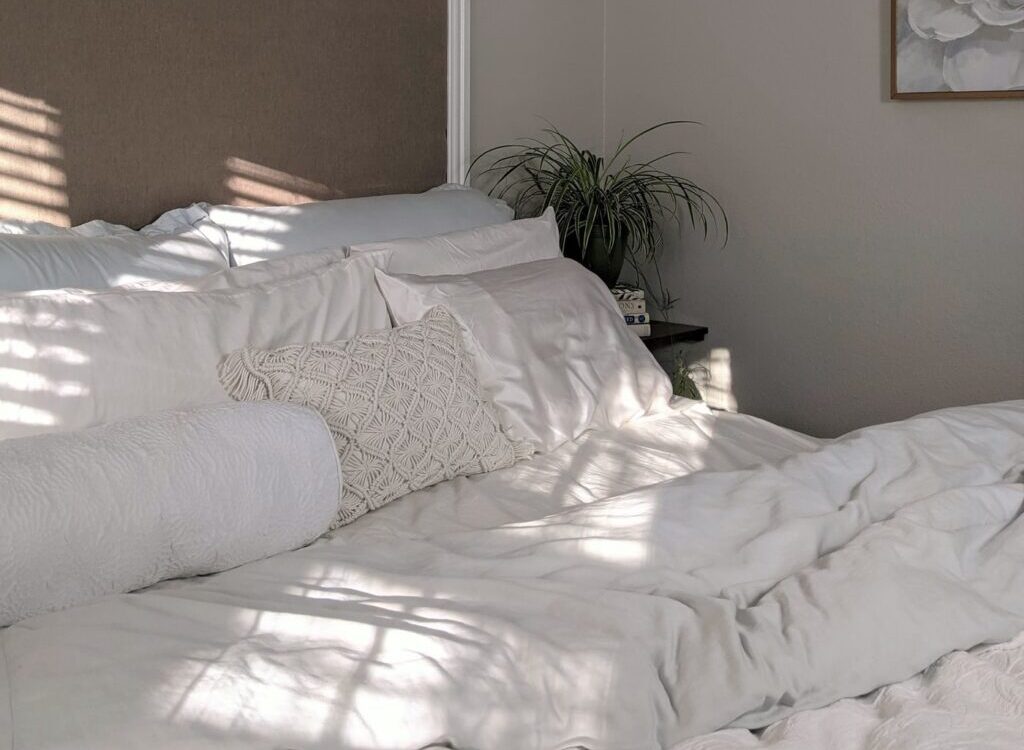 white bed linen near green plant