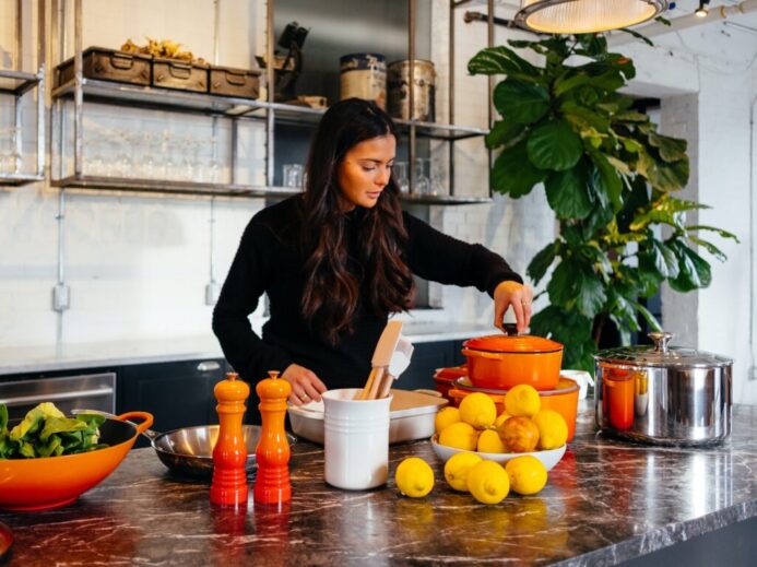 woman standing in front of fruits holding pot's lid