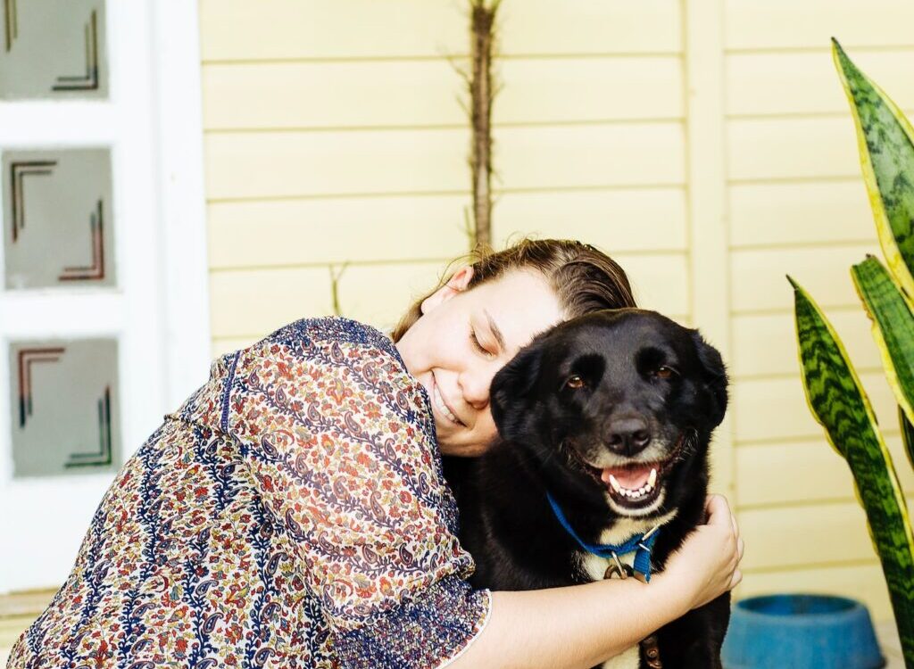 woman hugging black dog