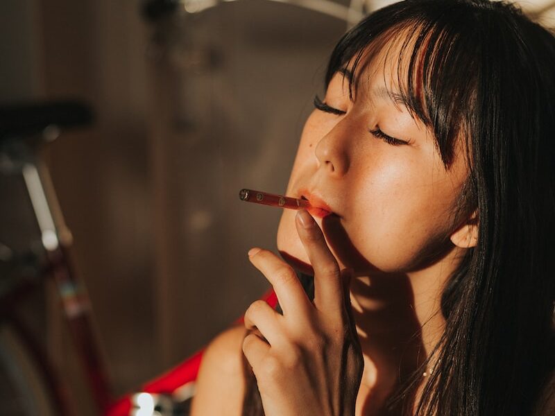 woman smoking cigarette while closing her eyes