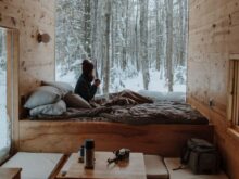 woman sitting on bed watching by the window during winter